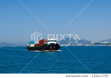 Container cargo ship with colorful containers sailing on Hong Kong Victoria Harbour on clear sunny day Container cargo ship with colorful containers sailing on Hong Kong Victoria Harbour on clear sunny day 138221787