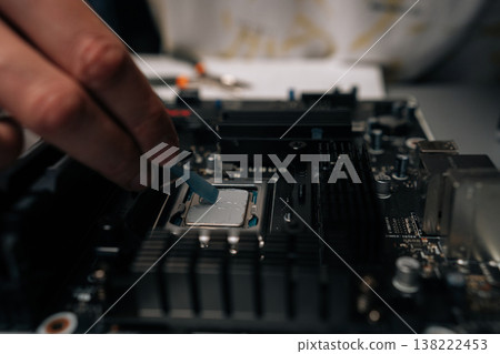 Technician applying thermal paste on computer processor, spreading precise layer for efficient cooling and improved performance during hardware maintenance. Concept of computer hardware, repairing. Technician applying thermal paste on computer processor, spreading precise layer for efficient cooling and improved performance during hardware maintenance. Concept of computer hardware, repairing. 138222453