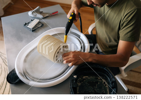 Top view of man cleaning humidifier filter using steam cleaner, removing dust and maintaining indoor air quality, thorough sanitizing technique. Concept of maintenance modern home appliance. Top view of man cleaning humidifier filter using steam cleaner, removing dust and maintaining indoor air quality, thorough sanitizing technique. Concept of maintenance modern home appliance. 138222571