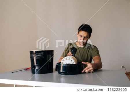 Portrait of skilled technician male cleaning air humidifier filter with vacuum cleaner, performing maintenance to ensure optimal air quality and promote healthy environment in home setting. 138222605