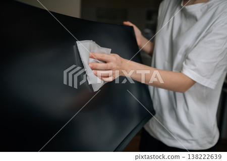 Cropped shot of person cleaning computer monitor screen with soft white cloth, wiping dust and smudges from display for improved hygiene and maintenance of electronic equipment. Cropped shot of person cleaning computer monitor screen with soft white cloth, wiping dust and smudges from display for improved hygiene and maintenance of electronic equipment. 138222639