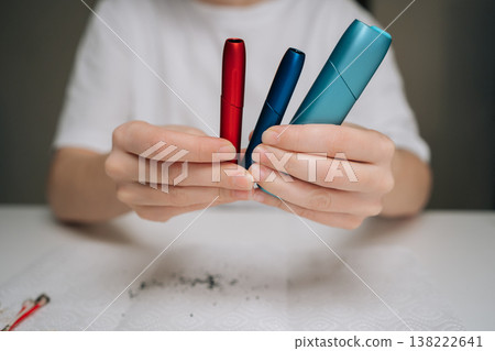 Hands holding colorful heat-not-burn electronic cigarettes after cleaning them, showing the importance of regular maintenance for device longevity and user experience, close-up cropped shot. Hands holding colorful heat-not-burn electronic cigarettes after cleaning them, showing the importance of regular maintenance for device longevity and user experience, close-up cropped shot. 138222641