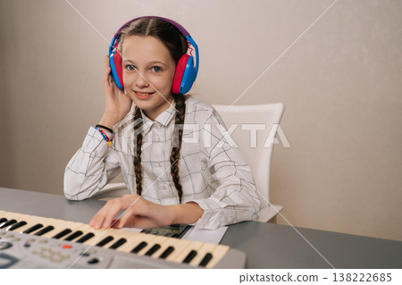 Young girl wearing headphones practicing digital piano, learning musical talent and developing concentration during education, enjoying creative hobby. 138222685