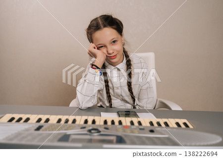 Tired young girl resting head on hand at digital piano, bored and weary during music lesson, needing a break from intense practice and concentration. Tired young girl resting head on hand at digital piano, bored and weary during music lesson, needing a break from intense practice and concentration. 138222694