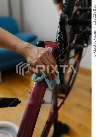 Bike mechanic spraying water on bicycle frame, wiping carefully with cloth during detailed workshop maintenance process, ensuring cleanliness and optimal performance. Concept of bicycle service. Bike mechanic spraying water on bicycle frame, wiping carefully with cloth during detailed workshop maintenance process, ensuring cleanliness and optimal performance. Concept of bicycle service. 138222816