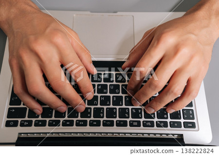 High-angle view of unrecognizable freelancer male typing on laptop keyboard, professional home office scene showing remote work, coding, online learning, business tasks and digital communication. High-angle view of unrecognizable freelancer male typing on laptop keyboard, professional home office scene showing remote work, coding, online learning, business tasks and digital communication. 138222824