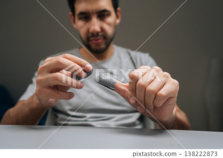 Serious focused man holding gaming thumb pads, preparing mobile device for enhanced gameplay, improving phone control responsiveness for competitive online performance, close-up, selective focus. Serious focused man holding gaming thumb pads, preparing mobile device for enhanced gameplay, improving phone control responsiveness for competitive online performance, close-up, selective focus. 138222873