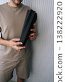 Man holding multiple black acoustic foam panels, preparing for the soundproofing process by applying insulation to a wall for recording studio or home audio setup. 138222920