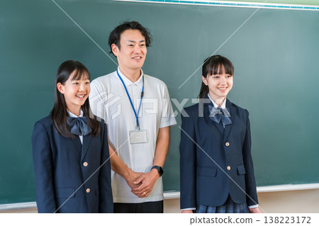 教室黑板前,一位男老師和一群小學、國中和高中的女生 教室黑板前,一位男老師和一群小學、國中和高中的女生 138223172