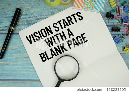 Vision Starts with a Blank Page text on a paper surrounded by office supplies and magnifying glass on a blue wooden surface 138223505
