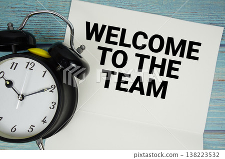 Notepad on a blue wooden table with the words "Welcome to the Team" and alarm clock Notepad on a blue wooden table with the words "Welcome to the Team" and alarm clock 138223532