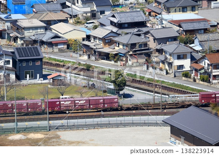 A freight train running past a residential area. A freight train running past a residential area. 138223914