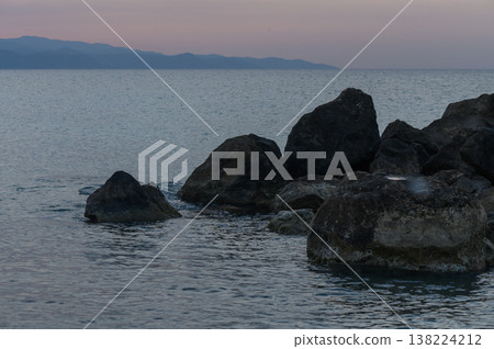 Tranquil twilight over rugged rocks and gentle waves by the serene coastline at dusk Tranquil twilight over rugged rocks and gentle waves by the serene coastline at dusk 138224212
