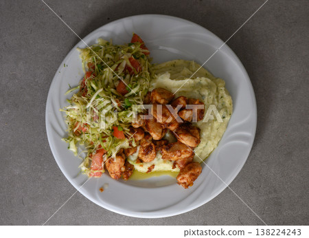 Delicious meal featuring spicy chicken with creamy mashed potatoes and fresh cabbage salad in a cozy dining setting Delicious meal featuring spicy chicken with creamy mashed potatoes and fresh cabbage salad in a cozy dining setting 138224243