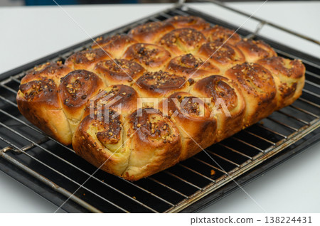 Freshly baked loaf of golden, pillowy rolls adorned with vibrant spices cooling on a rack in a cozy kitchen setting during the afternoon Freshly baked loaf of golden, pillowy rolls adorned with vibrant spices cooling on a rack in a cozy kitchen setting during the afternoon 138224431