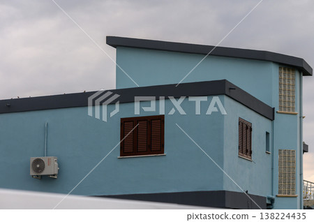 Modern blue building against a cloudy sky with an urban feel and contemporary design in the neighborhood Modern blue building against a cloudy sky with an urban feel and contemporary design in the neighborhood 138224435