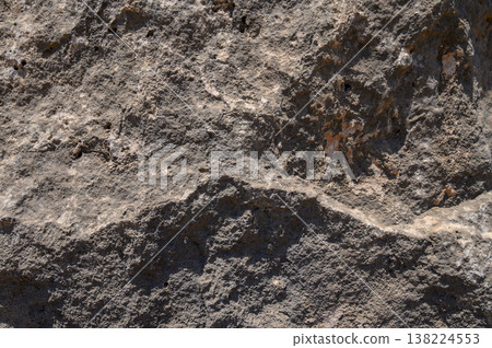 Unique texture of ancient rock formation bathed in sunlight at midday in a remote natural landscape Unique texture of ancient rock formation bathed in sunlight at midday in a remote natural landscape 138224553