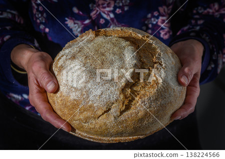 Freshly baked round loaf held by hands in a cozy kitchen setting, showcasing the art of bread making Freshly baked round loaf held by hands in a cozy kitchen setting, showcasing the art of bread making 138224566
