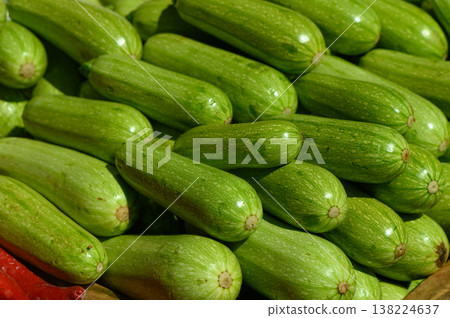 Freshly harvested green zucchinis stacked together at a vibrant local market in mid-summer sunshine Freshly harvested green zucchinis stacked together at a vibrant local market in mid-summer sunshine 138224637