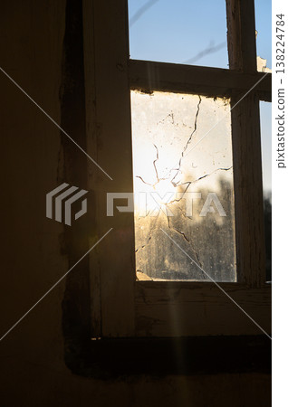 Sunrise breaks through a cracked window in an abandoned building Sunrise breaks through a cracked window in an abandoned building 138224784