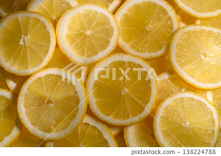 Bright yellow lemon slices layered beautifully on a textured surface showcasing 138224788
