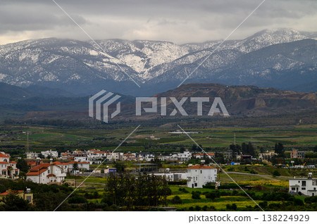 Majestic mountains cradle a tranquil village under a cloudy sky in early spring 138224929