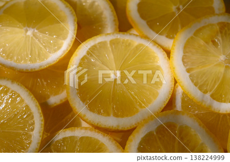 Fresh lemon slices arranged artfully on a wooden board, capturing vibrant yellow hues and juicy textures Fresh lemon slices arranged artfully on a wooden board, capturing vibrant yellow hues and juicy textures 138224999