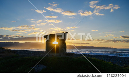 Sunset illuminates an ancient stone structure by the serene ocean shore in tranquil evening light Sunset illuminates an ancient stone structure by the serene ocean shore in tranquil evening light 138225004