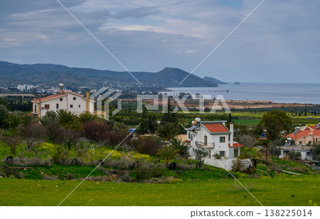 Tranquil coastal village nestled among hills and lush green fields on day Tranquil coastal village nestled among hills and lush green fields on day 138225014