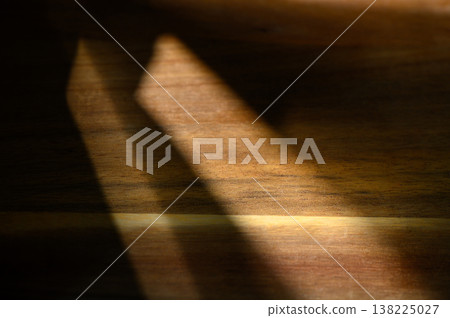 Play of light and shadow on a wooden surface creates a warm, textured ambiance 138225027