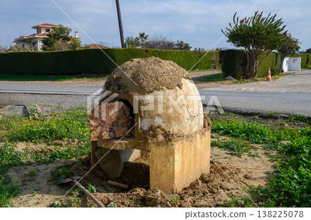 Traditional earthen oven stands by roadside as vegetation grows surrounding it Traditional earthen oven stands by roadside as vegetation grows surrounding it 138225078