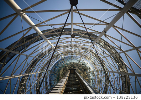 Low Angle View of Futuristic Steel Lattice Tower against Clear Blue Sky, Modern Architectural Engineering and Industrial Geometric Structure, Abstract Vertical Perspective Photography. Low Angle View of Futuristic Steel Lattice Tower against Clear Blue Sky, Modern Architectural Engineering and Industrial Geometric Structure, Abstract Vertical Perspective Photography. 138225136