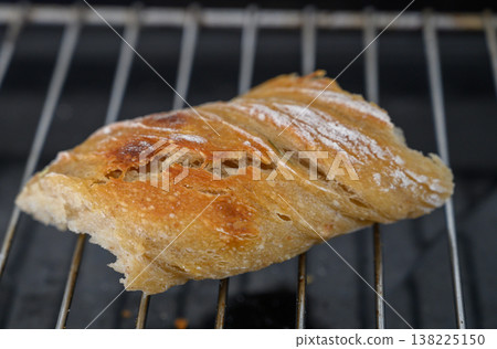 Freshly baked bread resting on a cooling rack, capturing warmth and texture in a cozy kitchen setting Freshly baked bread resting on a cooling rack, capturing warmth and texture in a cozy kitchen setting 138225150