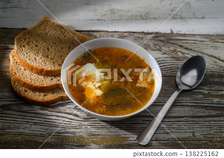 Warm bowl of homemade soup served with rustic bread on a wooden table during Warm bowl of homemade soup served with rustic bread on a wooden table during 138225162