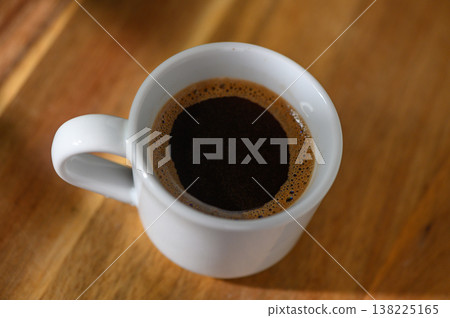 Rich aroma fills the air as a steaming cup of coffee sits on a wooden table Rich aroma fills the air as a steaming cup of coffee sits on a wooden table 138225165