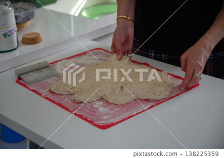 Hands skillfully kneading a dough on a bright kitchen counter during a cozy afternoon baking session Hands skillfully kneading a dough on a bright kitchen counter during a cozy afternoon baking session 138225359