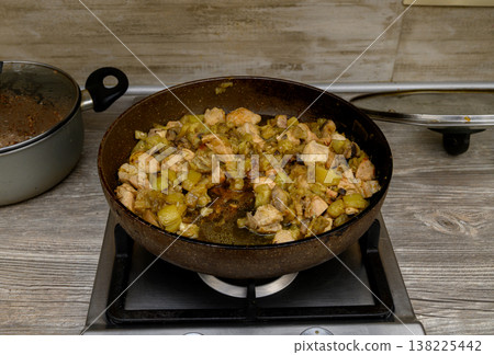 Chef Cooking Chicken and Zucchini Stir-Fry in a Pan on a Home Stove. Kitchen Scene. Chef Cooking Chicken and Zucchini Stir-Fry in a Pan on a Home Stove. Kitchen Scene. 138225442