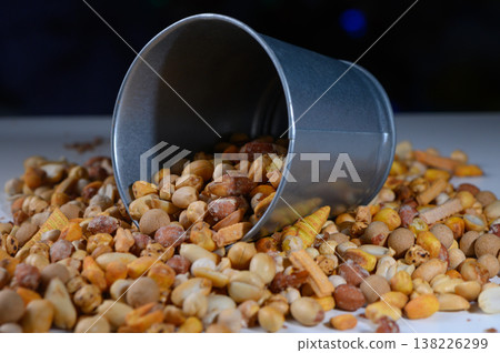 Colorful assortment of nuts and seeds spilling from a tipped metal bucket in a creative kitchen setup Colorful assortment of nuts and seeds spilling from a tipped metal bucket in a creative kitchen setup 138226299