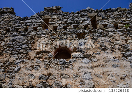 Stone-framed window inside the castle offering mountain views. Historical atmosphere and old architecture. Stone-framed window inside the castle offering mountain views. Historical atmosphere and old architecture. 138226318