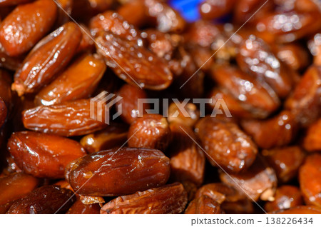 Rich and glossy Medjool dates piled together, showcasing their natural sweetness and vibrant color during a market display Rich and glossy Medjool dates piled together, showcasing their natural sweetness and vibrant color during a market display 138226434