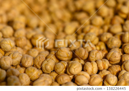 Dry chickpeas scattered in golden light highlight the texture and natural beauty of legumes in a warm setting 138226445