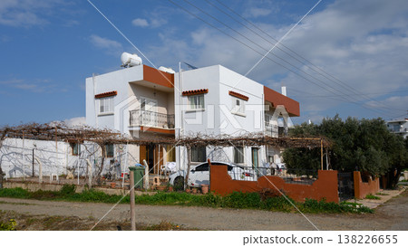 Charming white house surrounded by vines under a bright blue sky in a serene neighborhood Charming white house surrounded by vines under a bright blue sky in a serene neighborhood 138226655