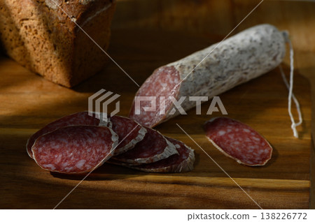 Savory salami slices arranged artistically beside rustic bread on a wooden board Savory salami slices arranged artistically beside rustic bread on a wooden board 138226772