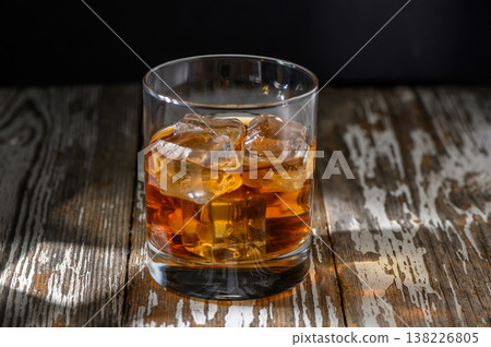 Enjoying a refreshing glass of whiskey on a rustic wooden table in the evening Enjoying a refreshing glass of whiskey on a rustic wooden table in the evening 138226805