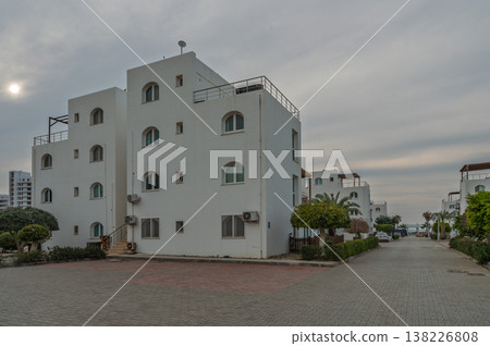 White buildings line a quiet coastal street under a cloudy sky in an idyllic seaside town White buildings line a quiet coastal street under a cloudy sky in an idyllic seaside town 138226808