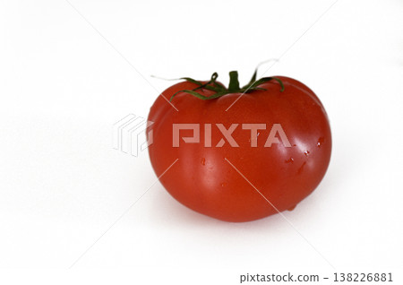 Fresh red tomato resting on a clean white surface before being sliced for a delicious salad Fresh red tomato resting on a clean white surface before being sliced for a delicious salad 138226881
