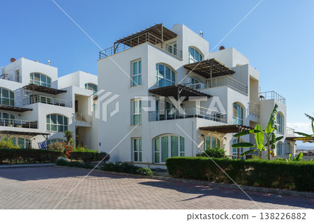 Elegant modern villa with balconies surrounded by lush greenery in a sunny Elegant modern villa with balconies surrounded by lush greenery in a sunny 138226882
