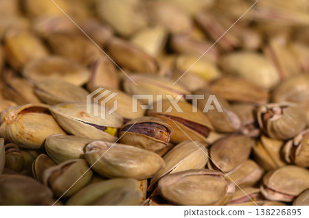 Pistachios scattered on a wooden surface create a natural and inviting texture in a rustic kitchen setting Pistachios scattered on a wooden surface create a natural and inviting texture in a rustic kitchen setting 138226895