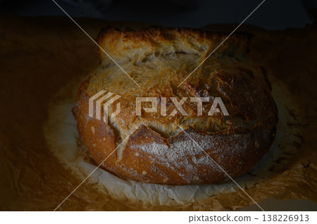 Freshly baked artisan bread resting on parchment with a golden crust Freshly baked artisan bread resting on parchment with a golden crust 138226913