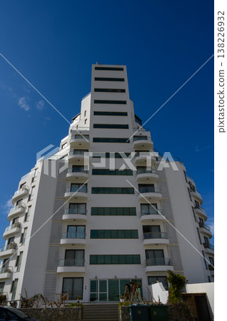 Modern architectural marvel stands tall against the brilliant blue sky in a vibrant cityscape Modern architectural marvel stands tall against the brilliant blue sky in a vibrant cityscape 138226932